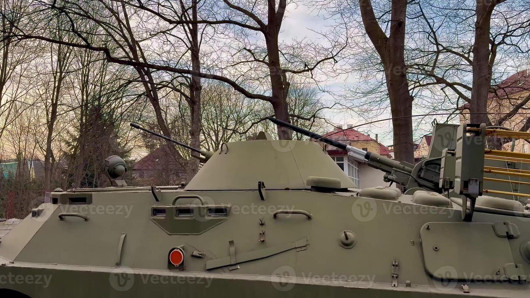 An armored vehicle is positioned among green trees, balancing nature and military might in a serene environment photo