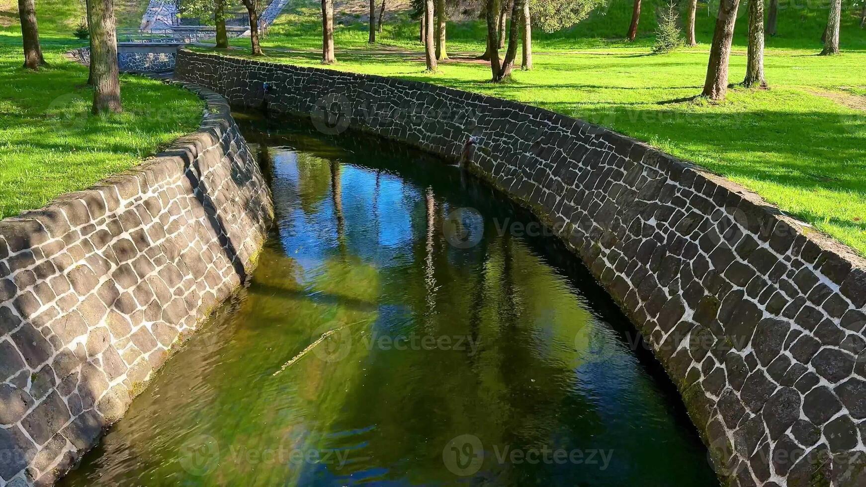 A serene and picturesque view of a winding stream gracefully flowing, surrounded by vibrant green grass and lush trees photo
