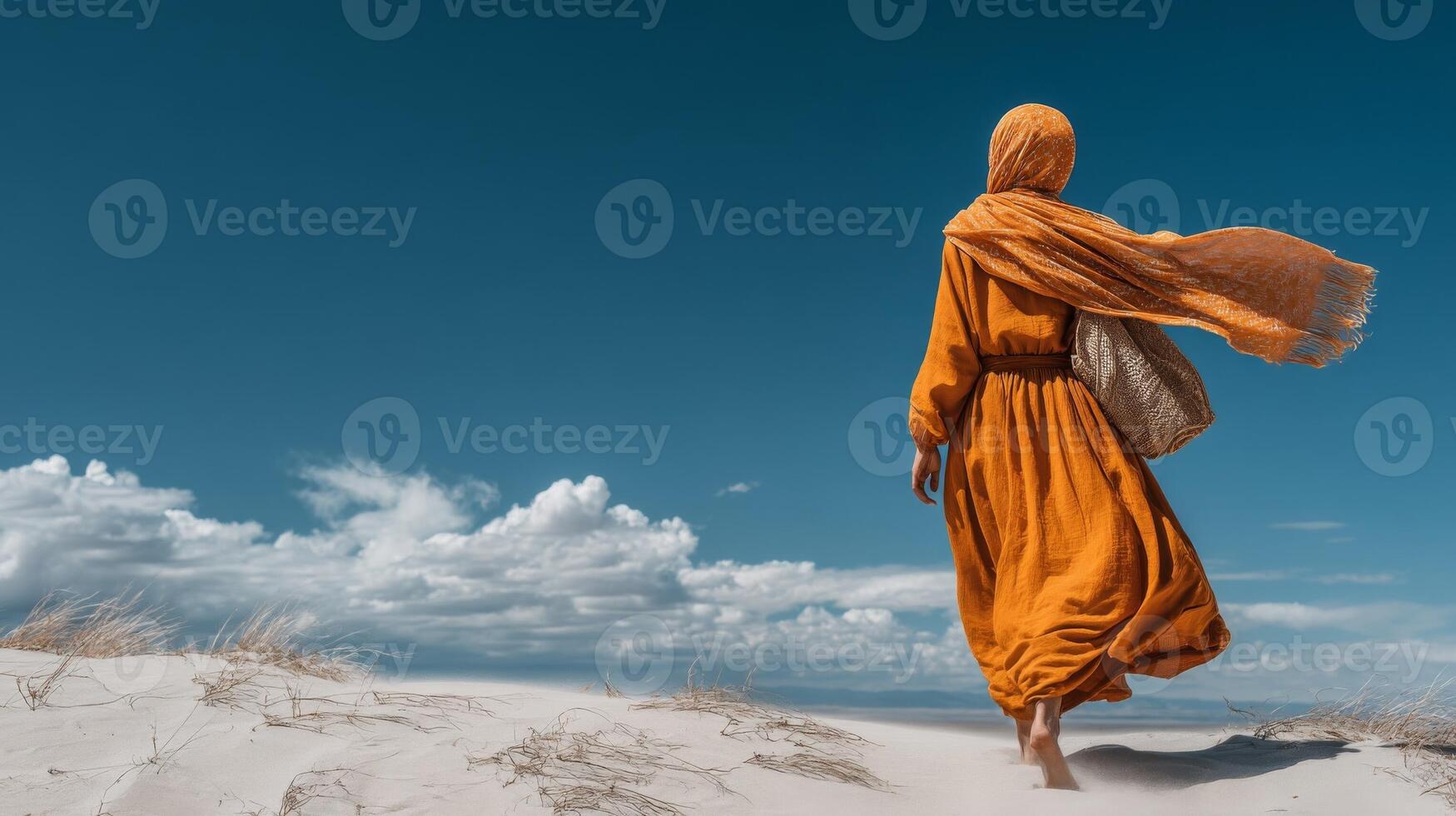 Woman in Orange Dress Walking on Sandy Desert Under Blue Sky photo