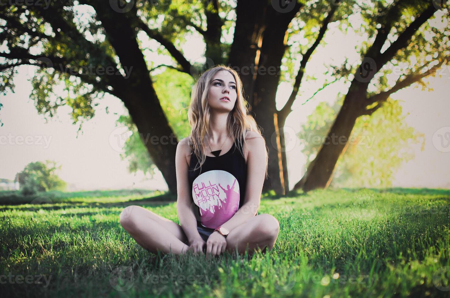 A woman in cropped black top on a background of Tall Green Tree photo