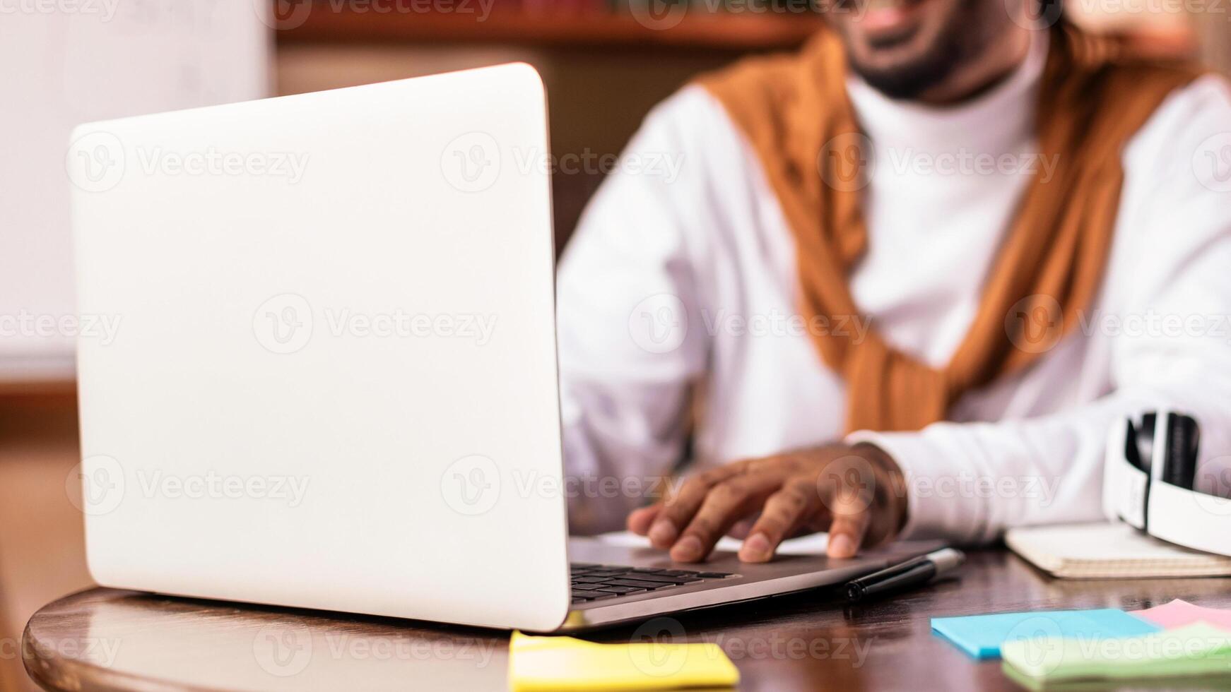Indian Guy At Laptop Learning Online Having Remote Webinar Making Online Lecture Class With Distant Teacher Sitting At Home. Focus On Computer. E-Learning, Distance Education Concept photo