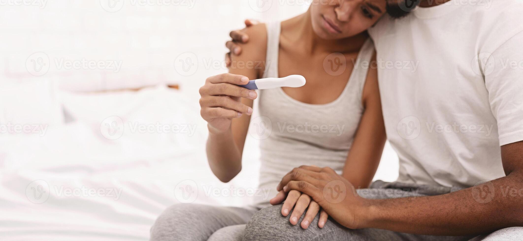 Couple dreaming to be parents. Upset african-american man and woman looking at negative pregnancy test, panorama with empty space photo