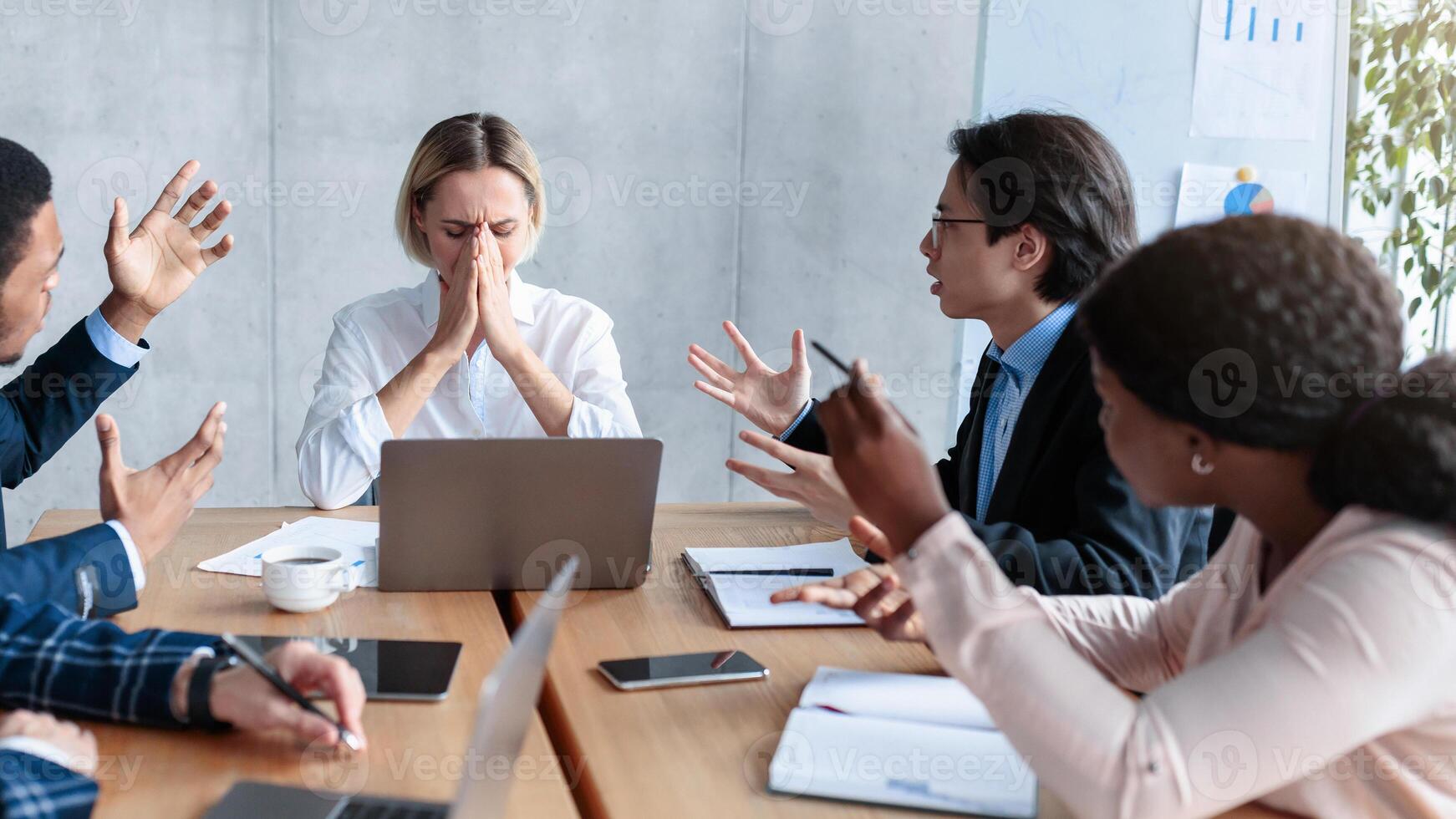 Aggressive Colleagues Shouting At Unhappy Victimized Business Lady Sitting At Desk In Modern Office. Problems And Disagreement At Work, Business Team Communication, Corporate Bullying Issue. Panorama photo
