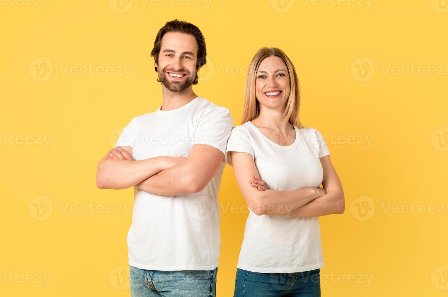 Smiling confident millennial caucasian guy and lady in white t-shirts with crossed arms on chest look at camera, isolated on yellow background. Love, relationship, ad and offer, facial expression photo