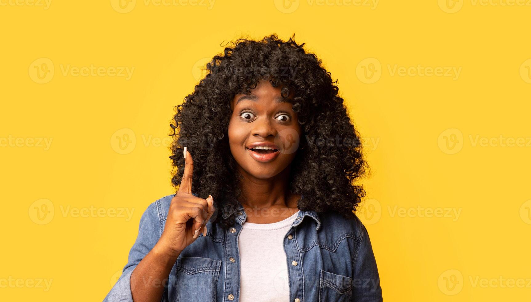 Inspiration, creativity, solution, eureka concept. Inspired young black woman in casual outfit raising finger up and smiling, having creative idea, yellow studio background, copy space photo
