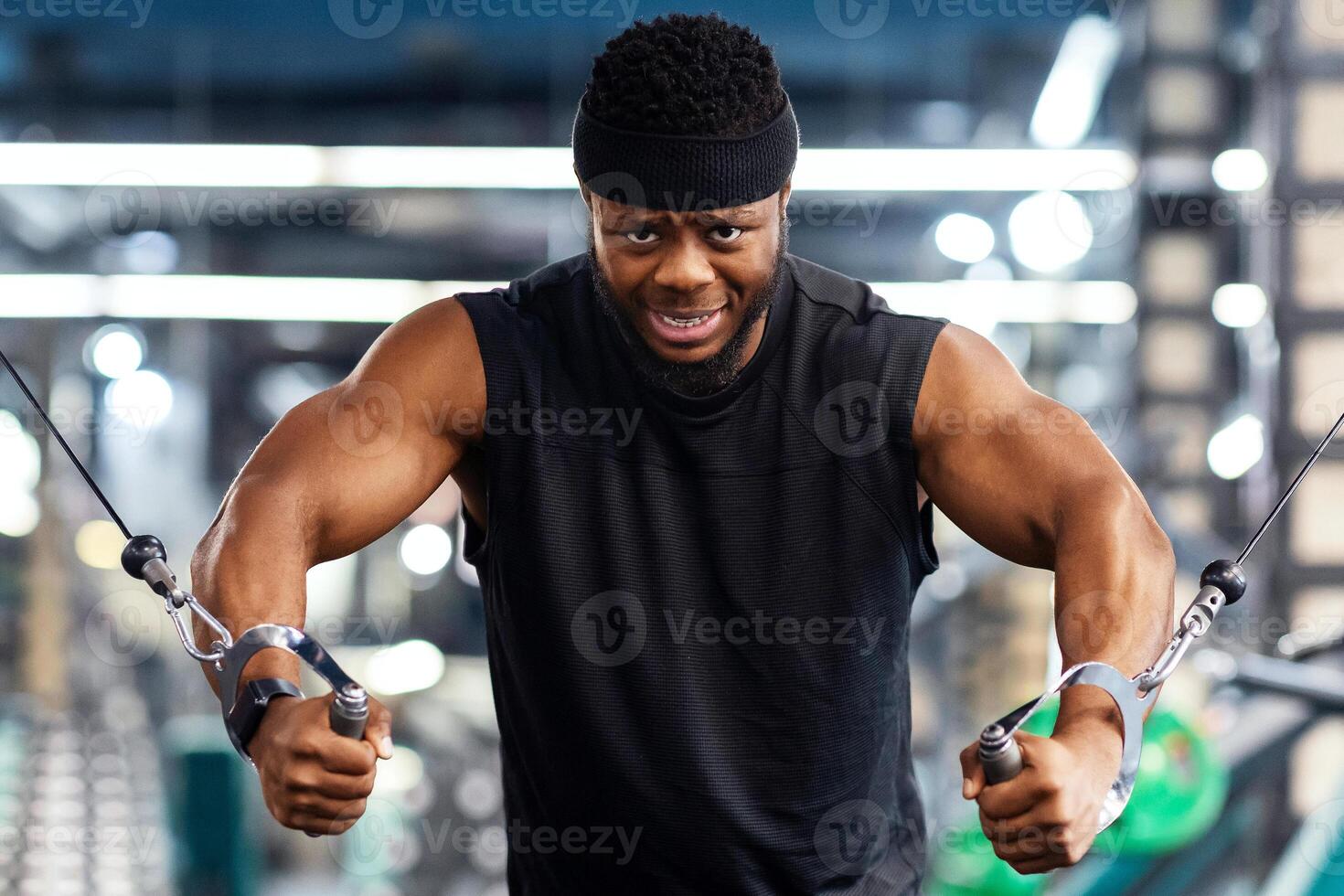 Motivated young black sportsman having workout on crossover machine. Handsome african american man bodybuilder training triceps on modern block exerciser in gym, copy space photo