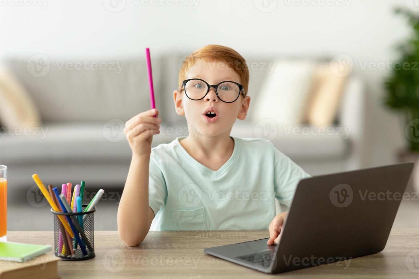 Inspired school kis redhead boy with glasses using laptop at home, raising hand with pencil up, smart preteen child showing eureka gesture, looking for creative solutions while studying, copy space photo