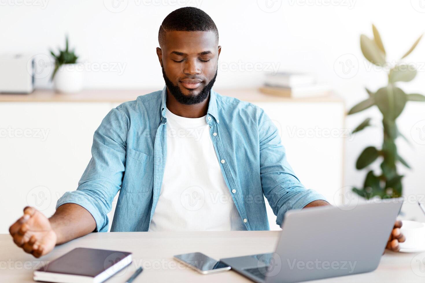 Coping With Working Stress. Portraif Of Calm Black Man Meditating At Workplace In Modern Office, Practicing Yoga, Young African American Entrepreneur Sitting At Desk With Closed Eyes While, Free Space photo