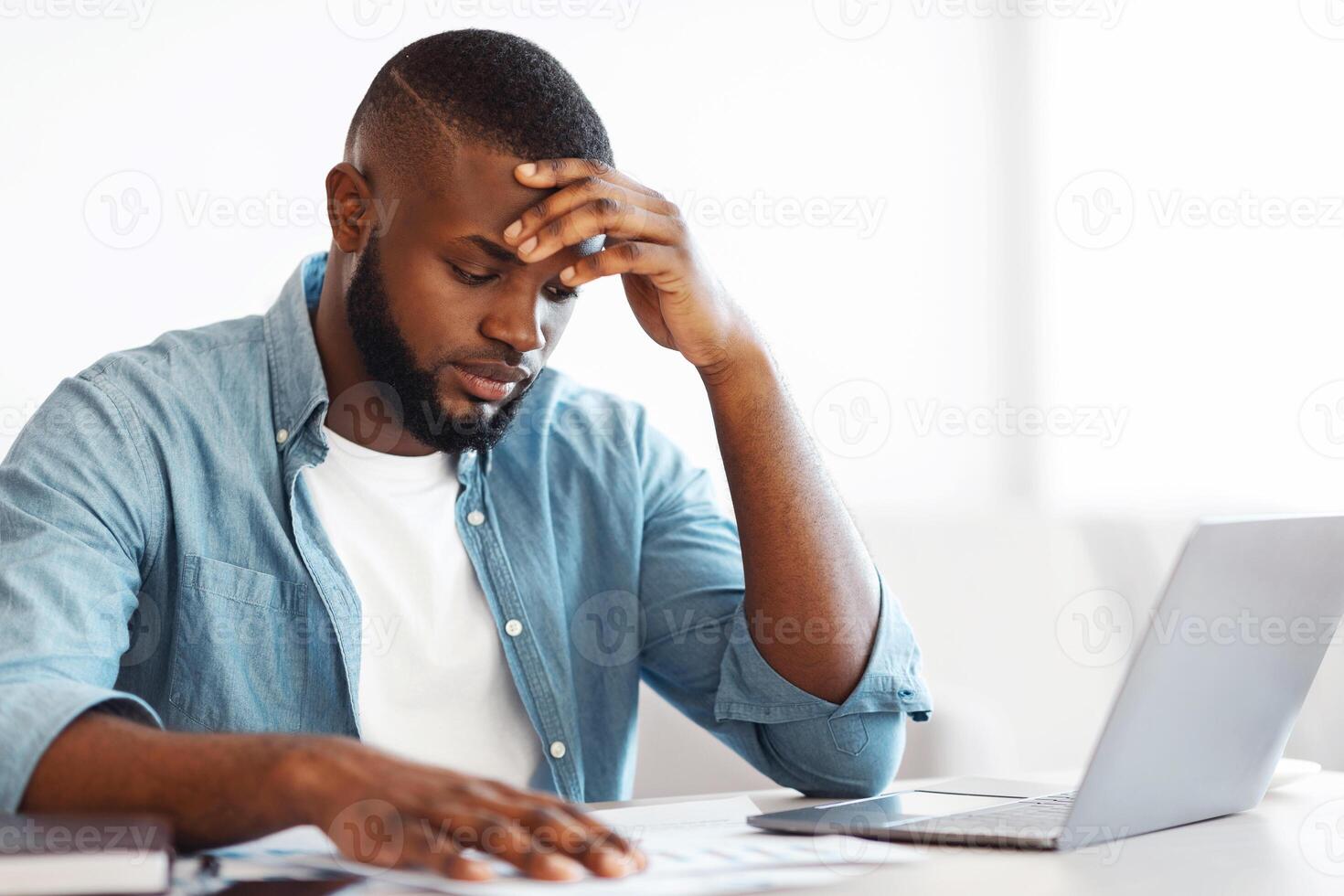 Work Troubles. Frustrated African American Businessman Reading Documents In Office, Sitting At Desk And Checking Financial Reports, Exhausted Black Millennial Man Feeling Sick And Tired, Free Space photo