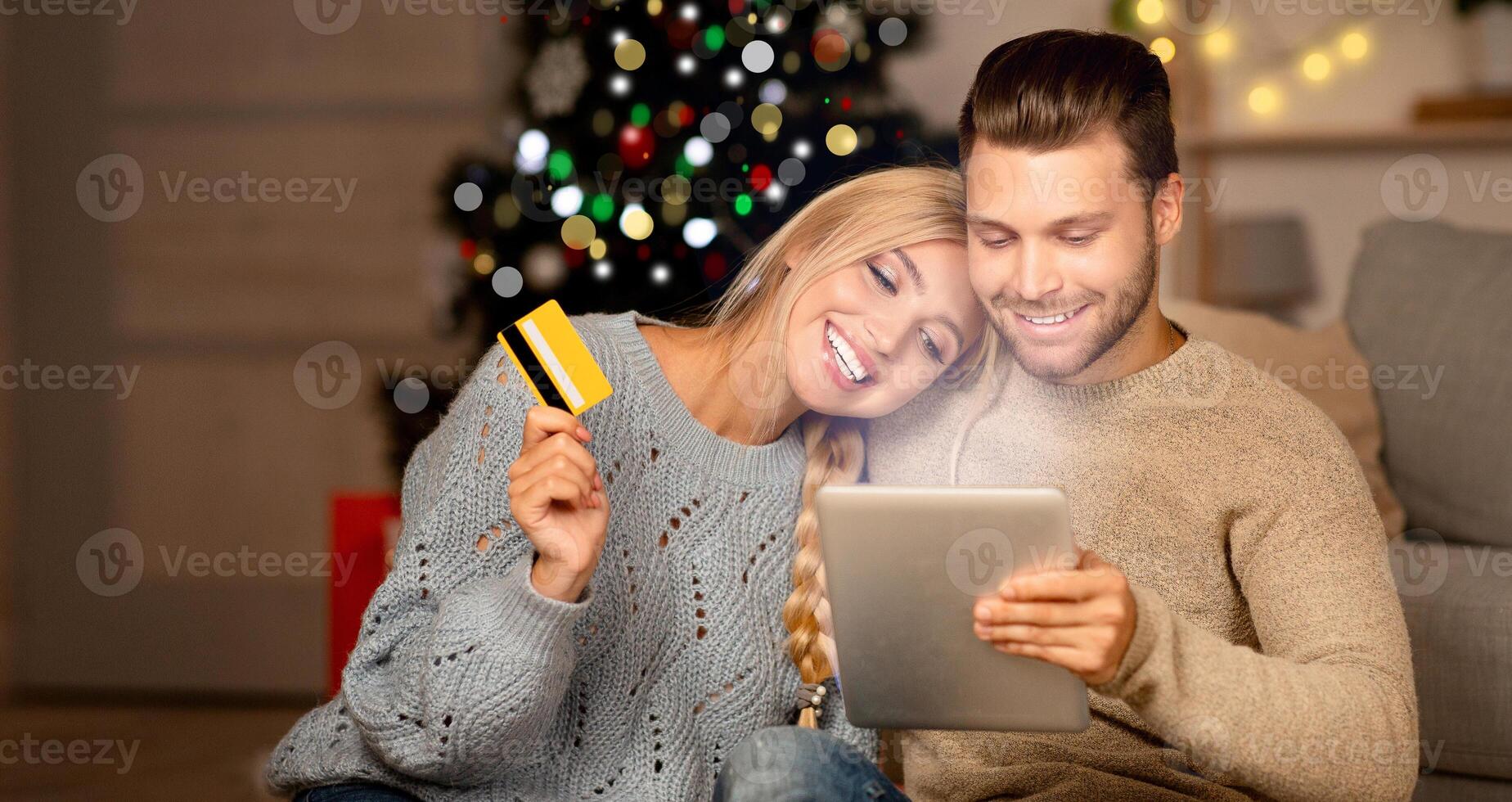 Holidays offers. Young happy family of shopaholics shopping online on digital tablet, home interior, copy space. Joyful couple with credit card and pad making purchases online, buying gifts photo
