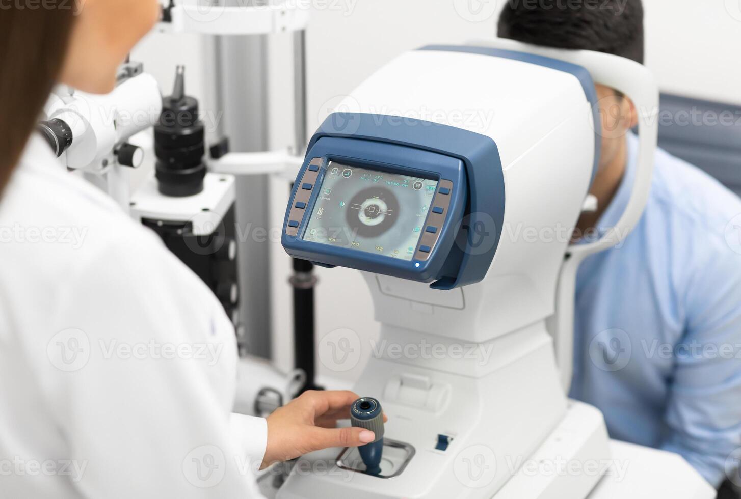 Eye Inspection Concept. Female ophthalmologist checking eye vision of young male customer in modern clinic, back view photo