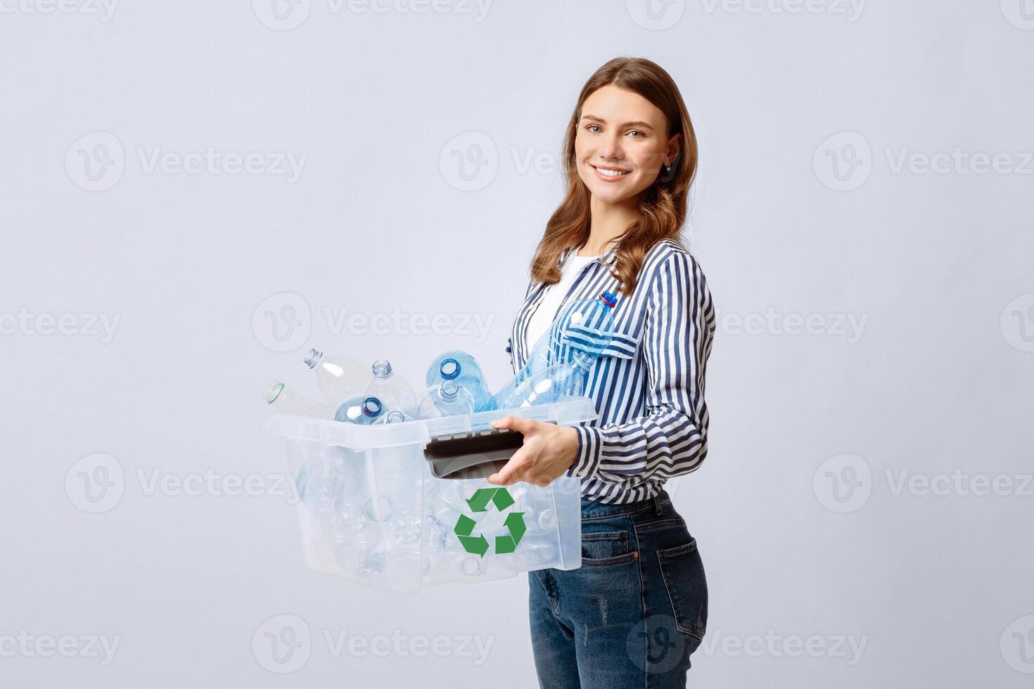 Recyclable Materials. Young Smiling Woman Holding Container With Empty Plastic Bottles For Recycling, Positive Eco-Volunteer Lady Enjoying Zero-Waste System, Standing Over Light Background, Free Space photo