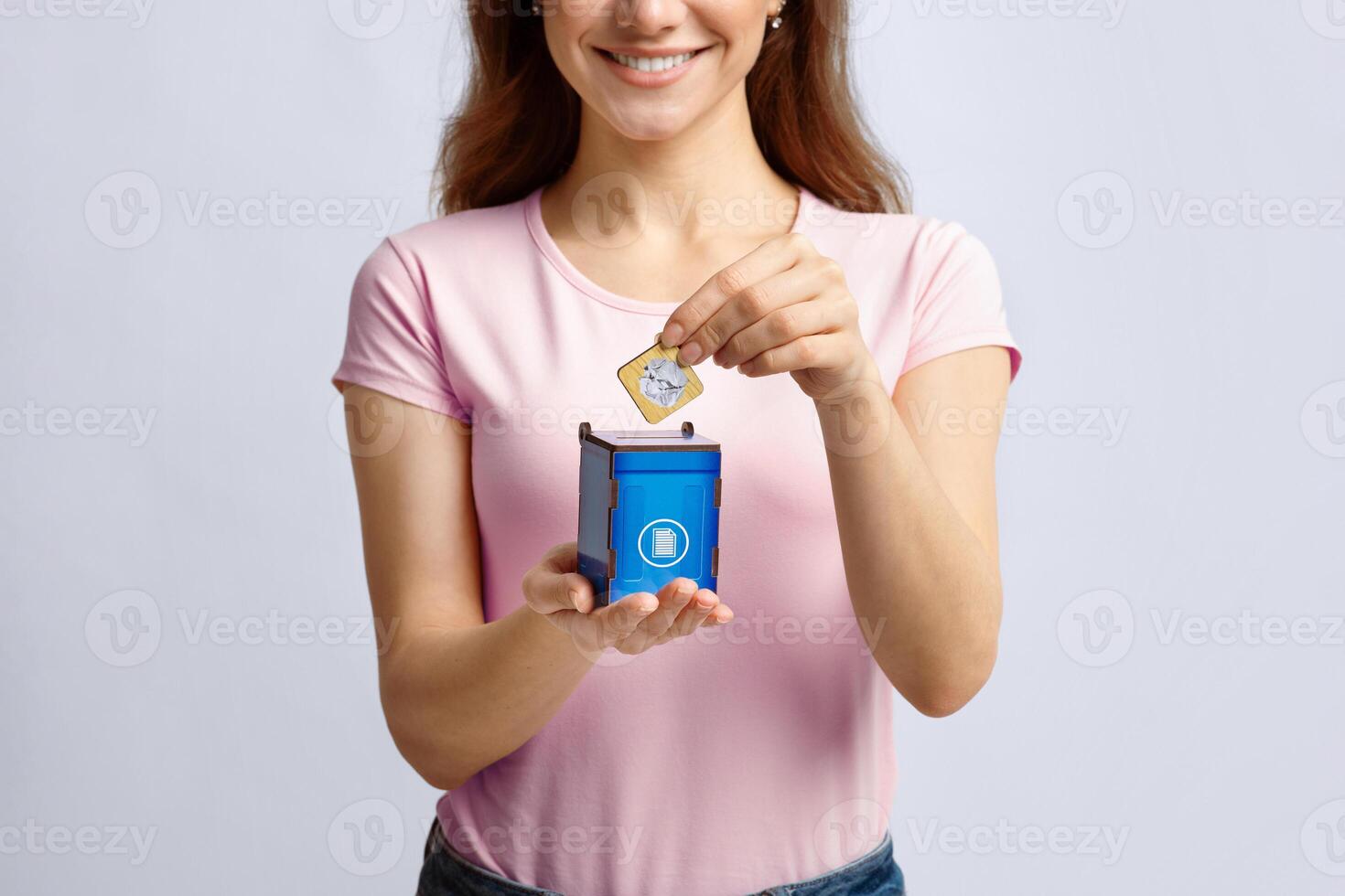 Garbage Sorting Conceptual Image With Woman Putting Card With Paper Waste Icon Into Small Wooden Toy Trash Container, Unrecognizable Lady Standing Over Light Background In Studio, Copy Space photo