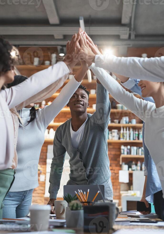 Young afro manager giving high five to his international team, having business meeting in office photo