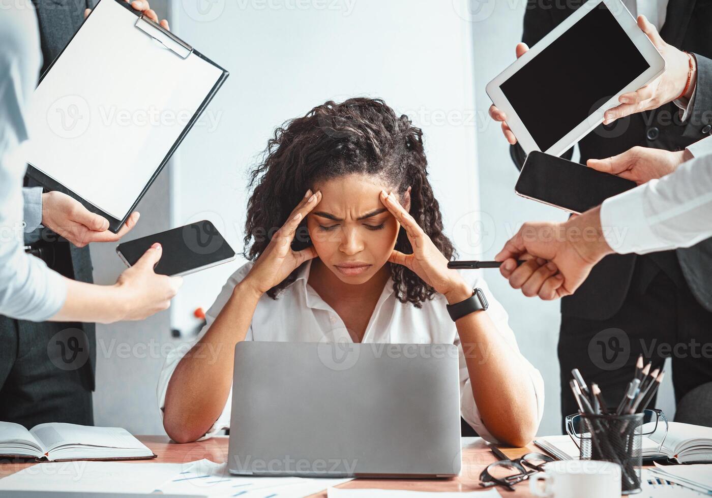 Multitasking. Overworked Afro Businesswoman Sitting Touching Head Ignoring Colleagues Tired Of Multiple Tasks At Work In Modern Office. photo