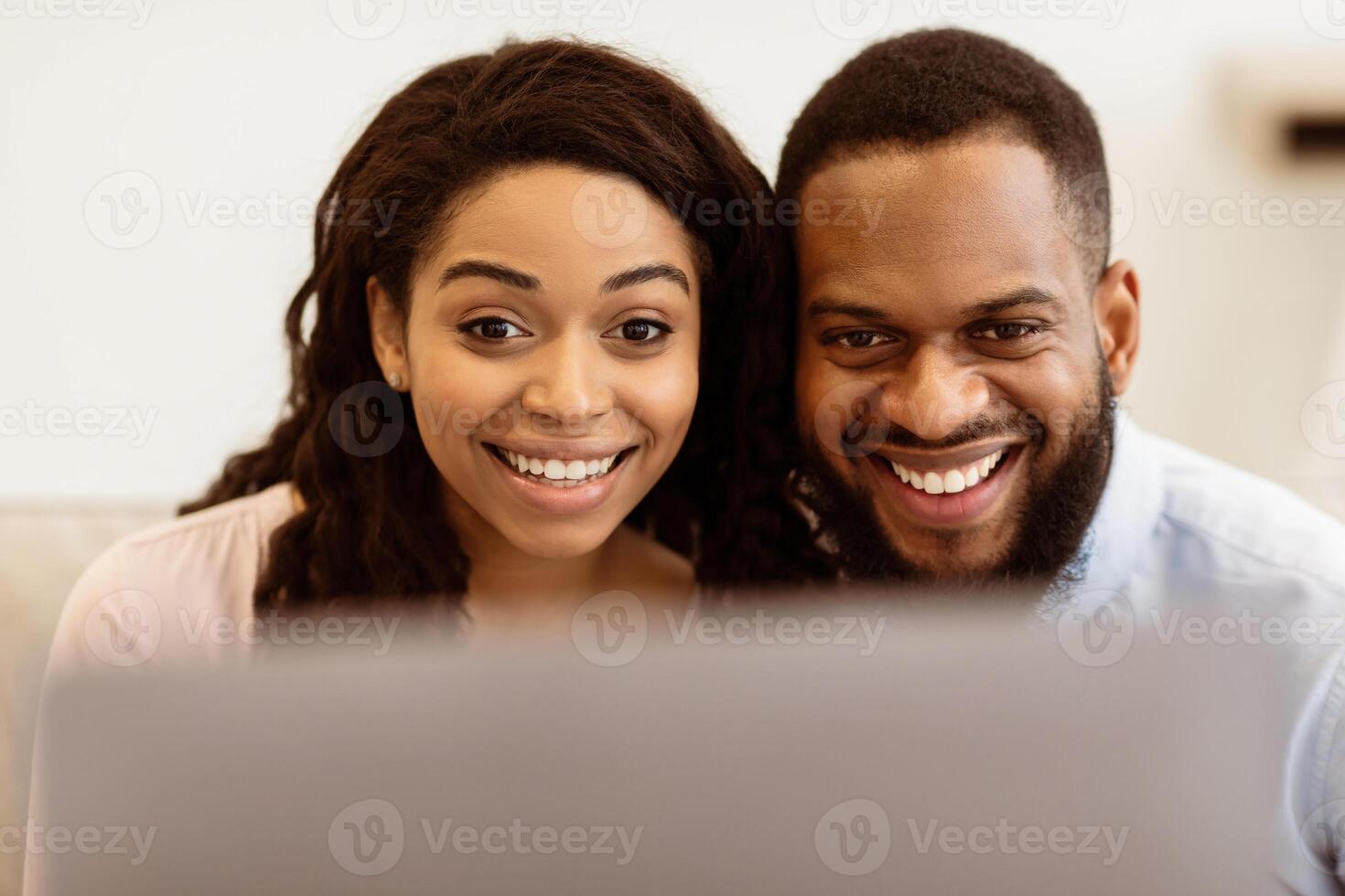 Technology Concept. Closeup portrait of smiling excited black couple using laptop computer, having online conference with friends or family, watching or movie spending time at home photo