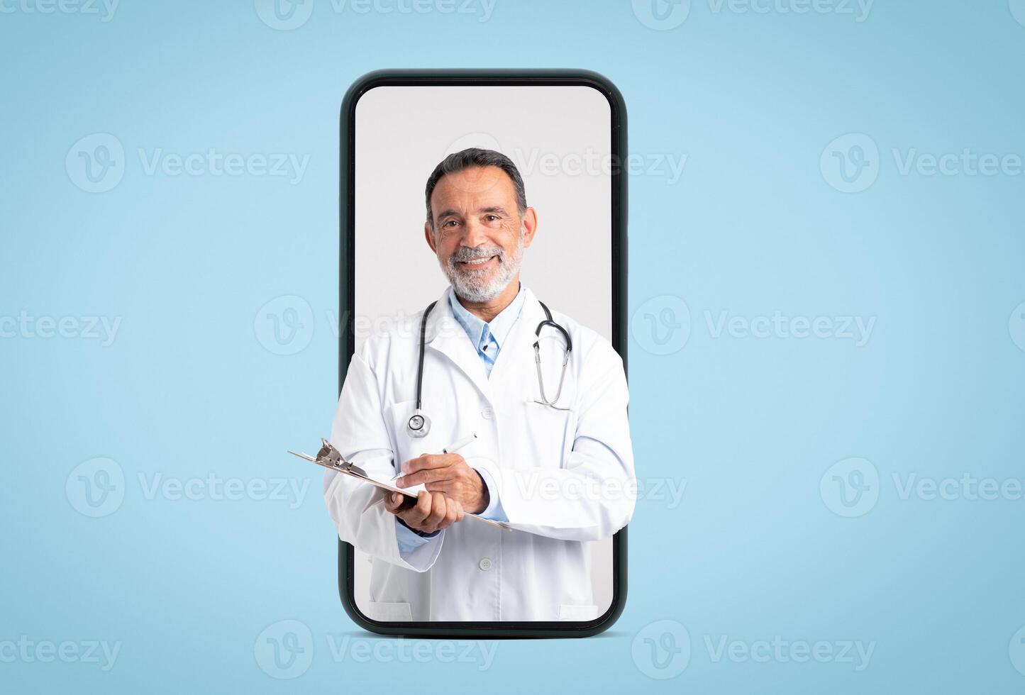 Happy confident european old doctor in white coat with stethoscope makes notes on big phone screen on blue background. App for medical help, diagnostics, exam, ad and offer photo
