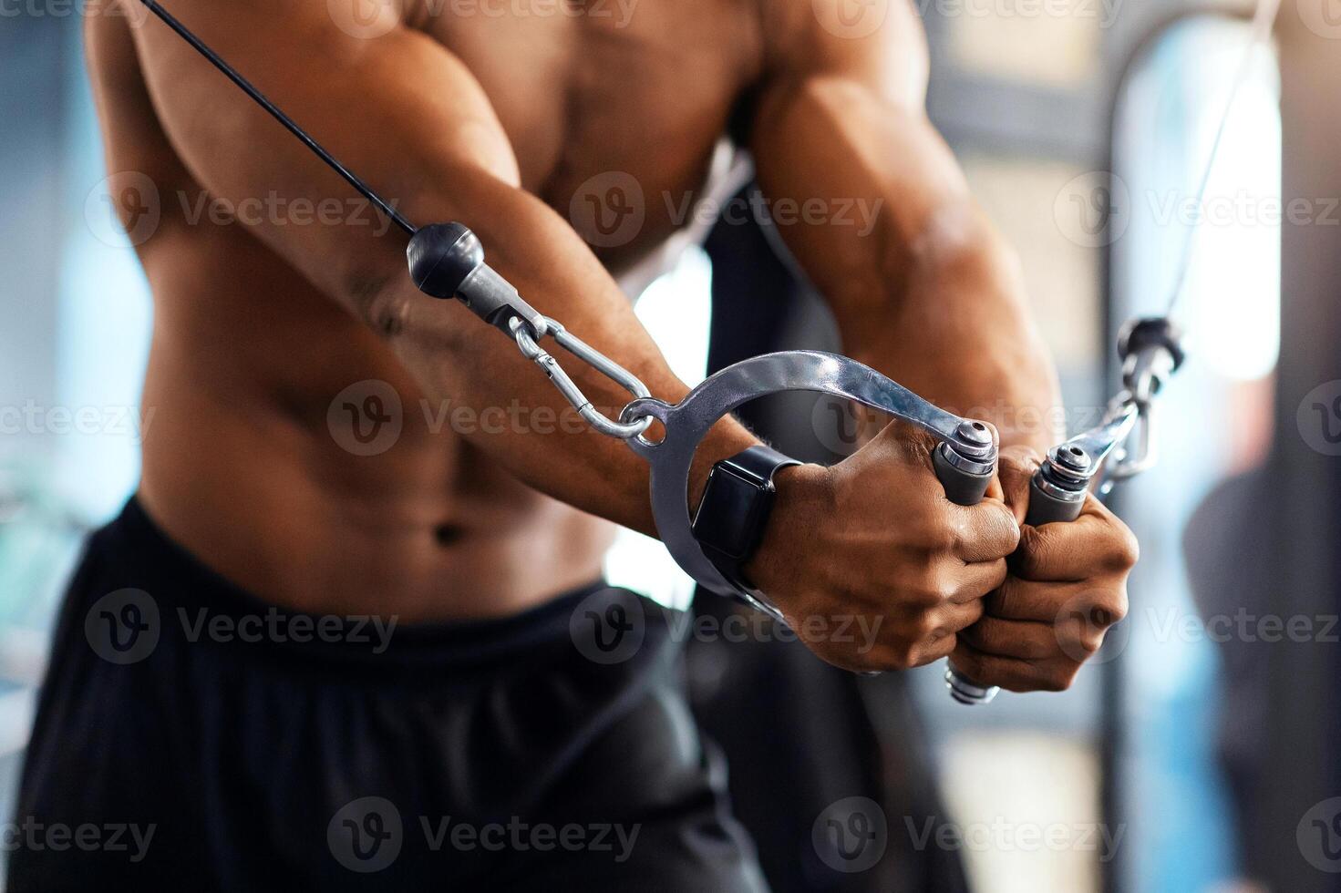 Cropped of black man athlete training triceps on block exerciser in gym, copy space. Unrecognizable african american bodybuilder having workout at modern gym, using crossover machine photo