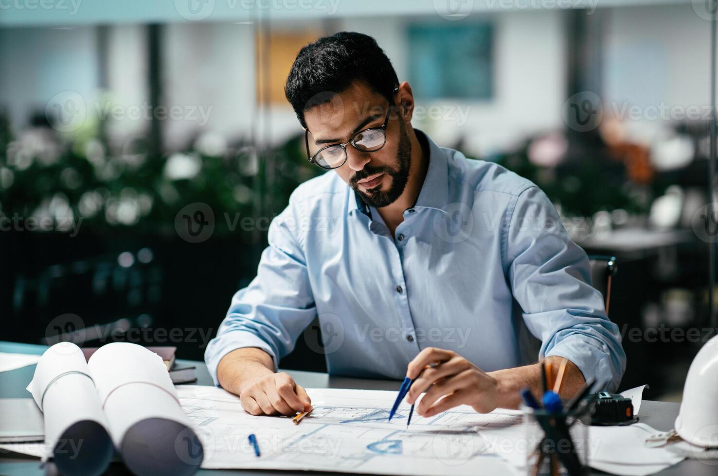Concentrated busy handsome millennial islamic male engineer with beard in glasses, think about project in office interior, professional architect work in factory. Solving construction planning problem photo