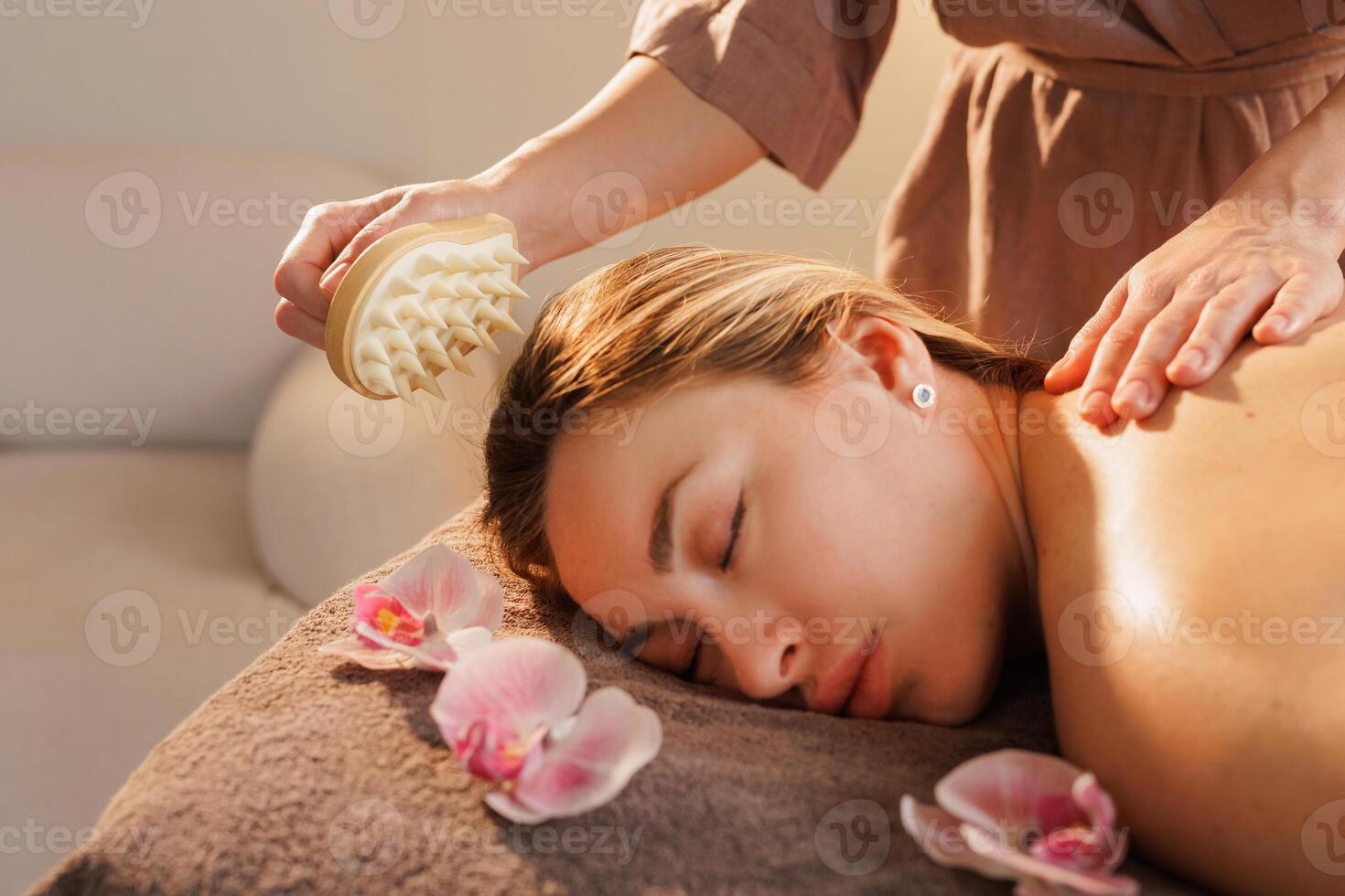 Therapist uses a spiked massage tool to gently stimulate the woman's scalp during a calming spa session, enhancing circulation, relaxation, and stress relief in a tranquil setting. photo