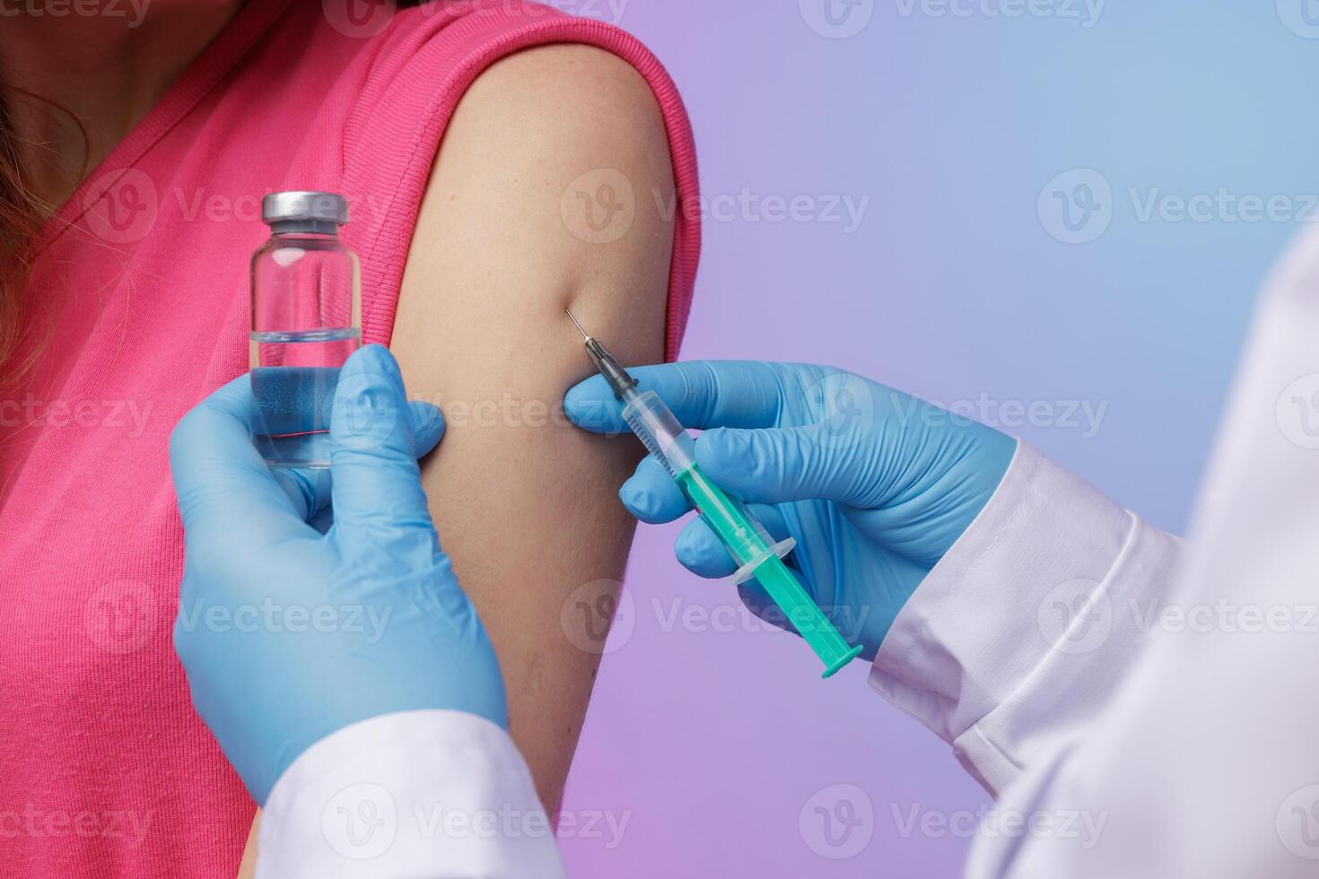 Close-up of a nurse giving an injection in the upper arm of a woman, holding a syringe and vaccine vial, symbolizing immunization, protection, and medical treatment. photo