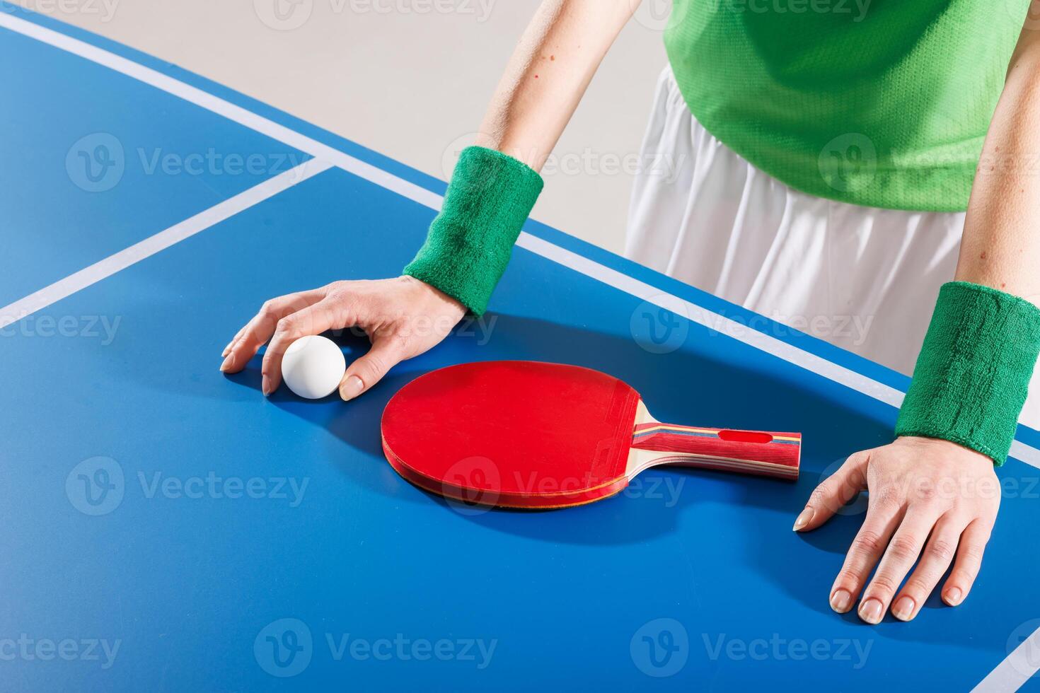Close-up of player resting paddle and ball on table tennis surface, ready to start the match. photo