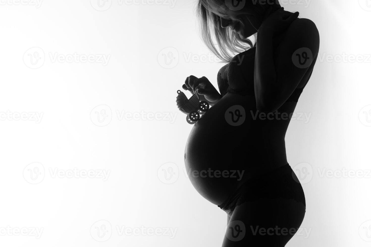 Silhouette of a Pregnant Woman Holding Baby Shoes photo