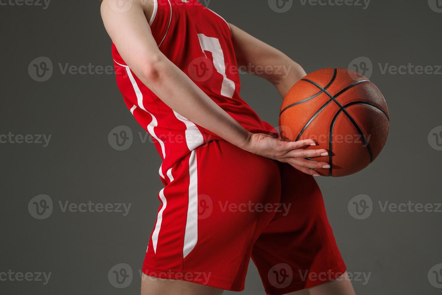 Female Basketball Player in Red Uniform Holding Ball Behind Back, Confident Sports Portrait photo