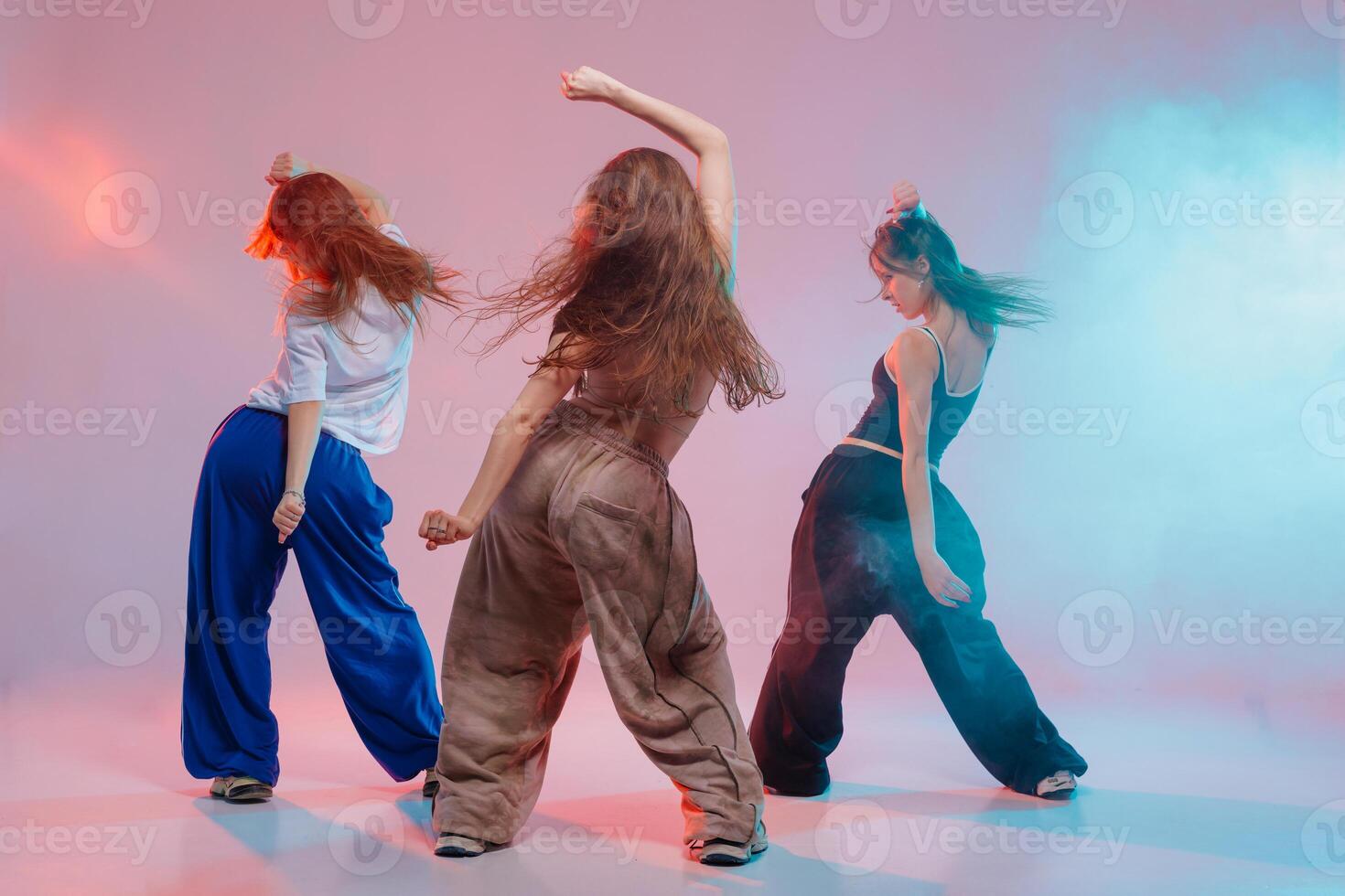 Three Young Women Dancing Jazz Funk in Studio with Colorful Lights and Dynamic Urban Movement photo
