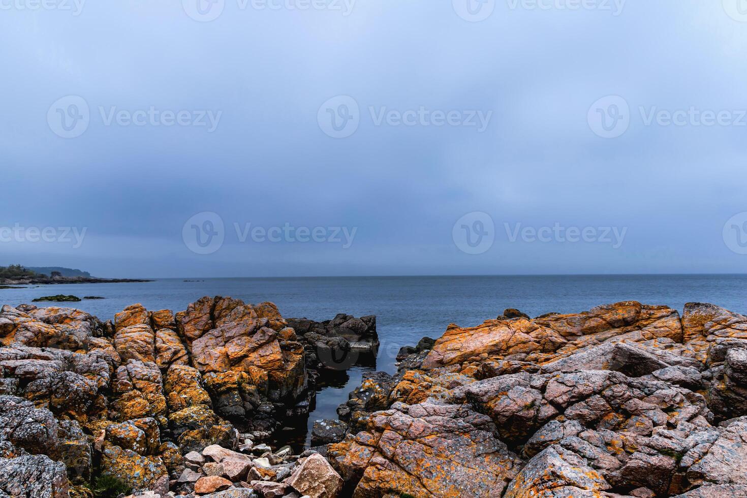 a view of a rocky shoreline with a lighthouse in the distance photo