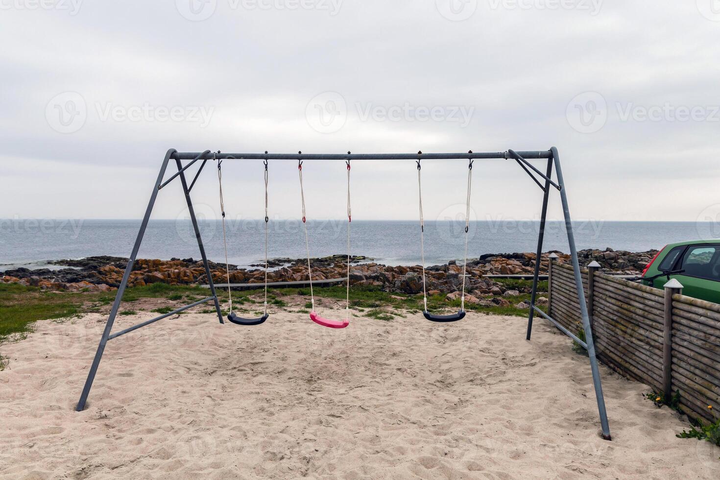 Empty children's swing on the seashore on a cloudy day photo