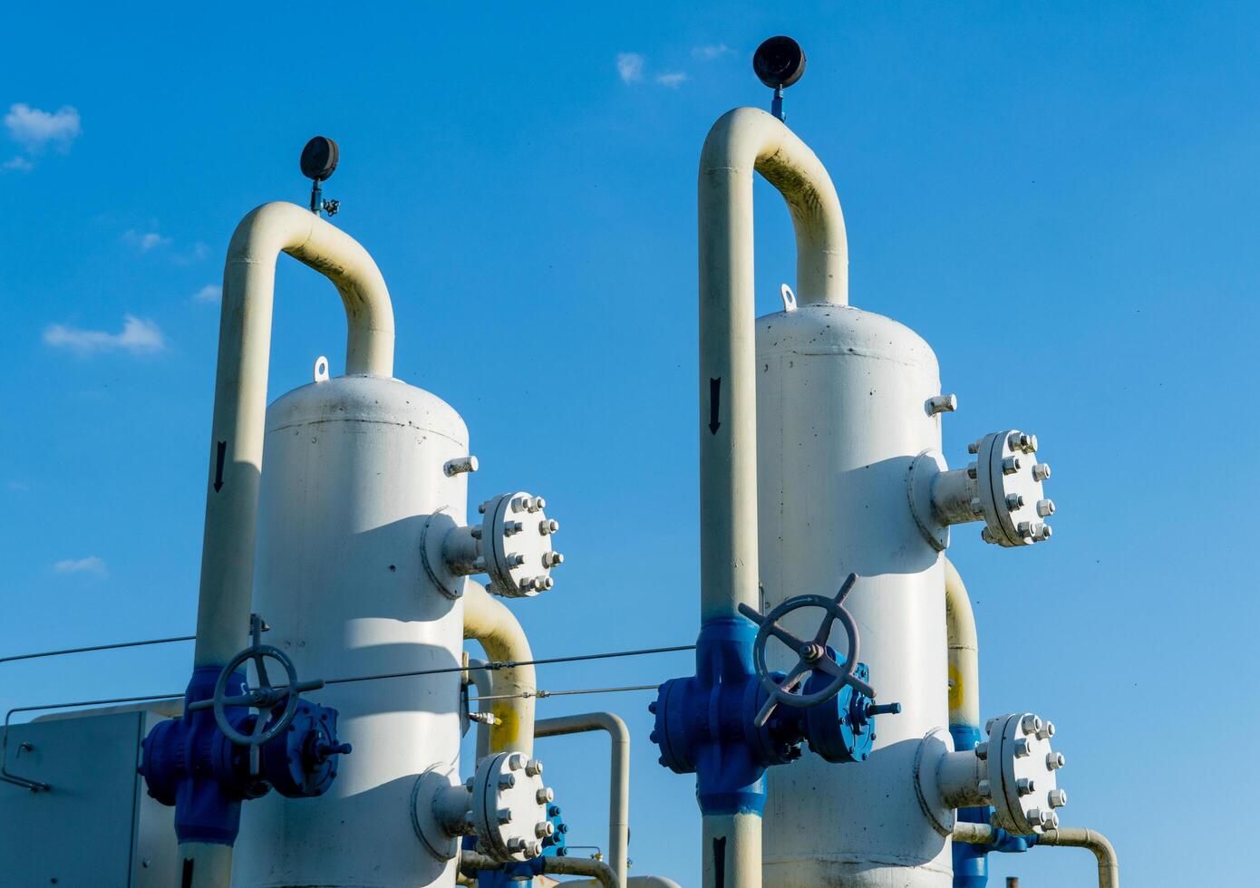 Two large pipes with valves on top of a blue sky photo