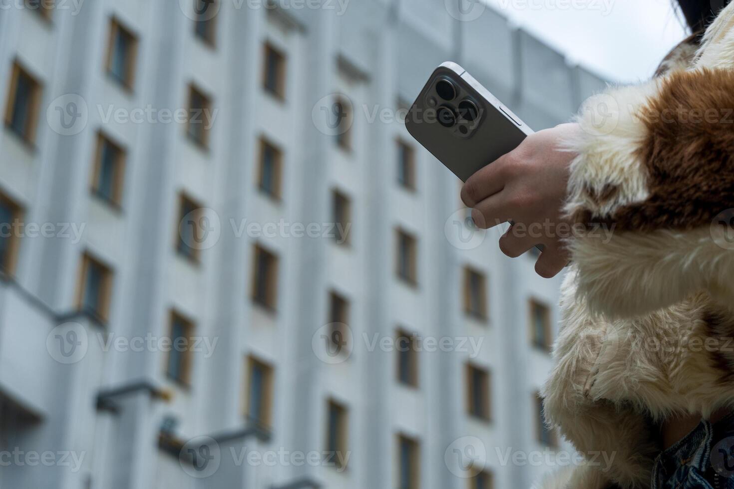 Hand Holding a Mobile Phone Against a Building Facade Outdoors photo