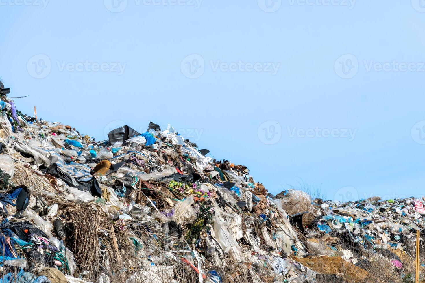 Vast Landfill Overflows with Piles of Discarded Waste Material Under Clear Blue Sky photo