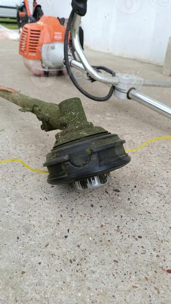 A detailed closeup view of a Grass Trimmer Head resting on a Concrete Surface nearby photo