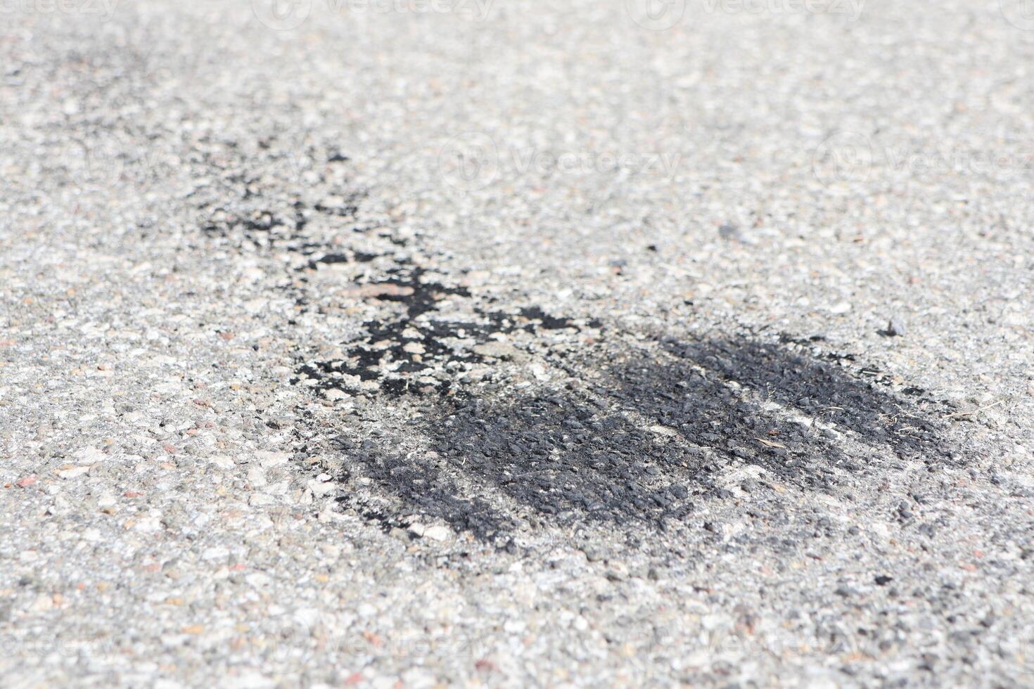 A Black Asphalt Smudge Visible on a Rough Concrete Surface, Showcasing Urban Elements and Details photo