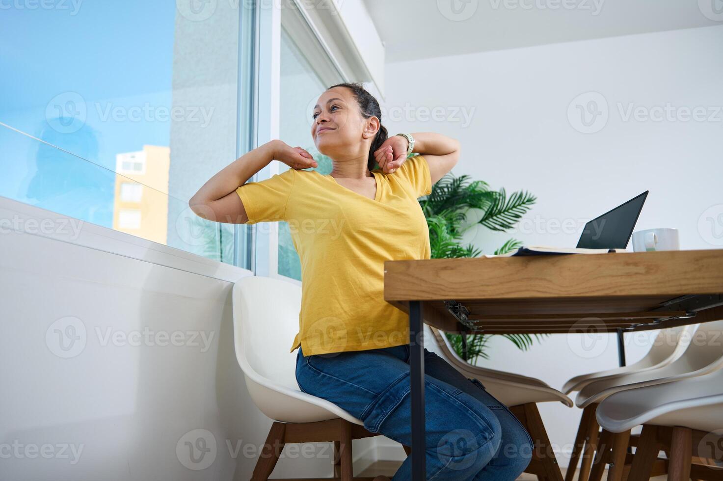 Woman Stretching With Relaxed Expression While Working at Home photo