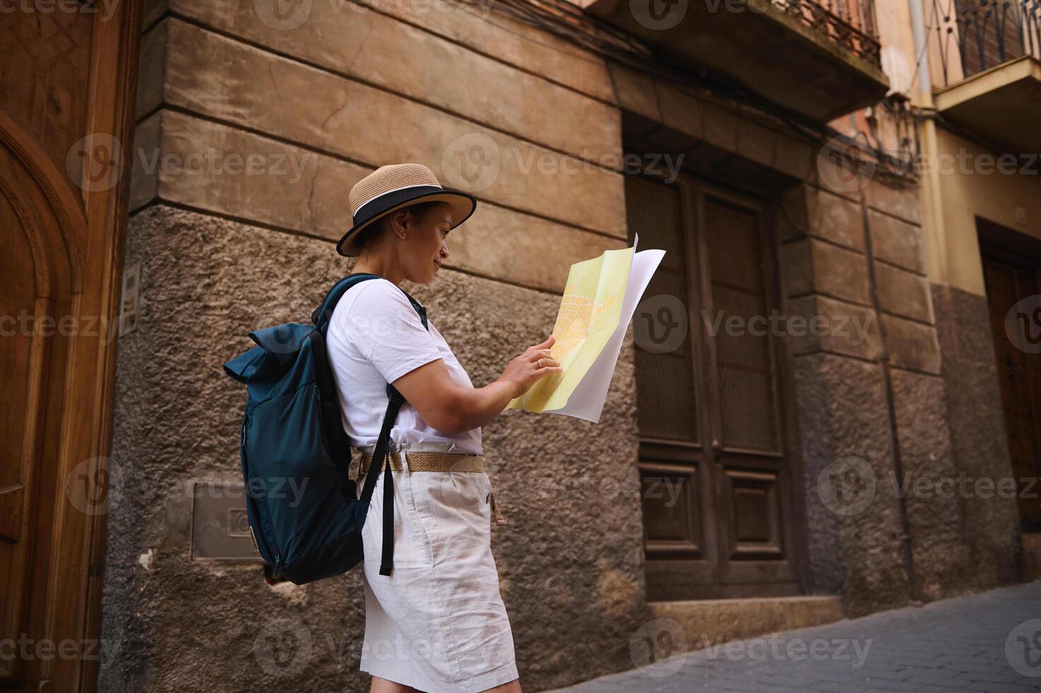 Woman Tourist Exploring a Historic City Street With a Map and Backpack photo