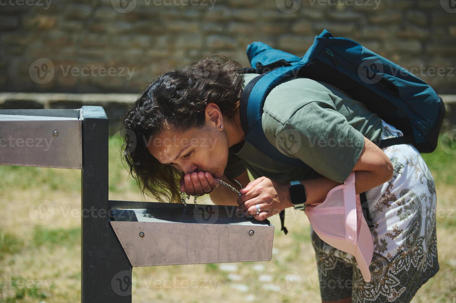 Young Woman Refreshing Herself at an Outdoor Drinking Fountain on a Sunny Day photo