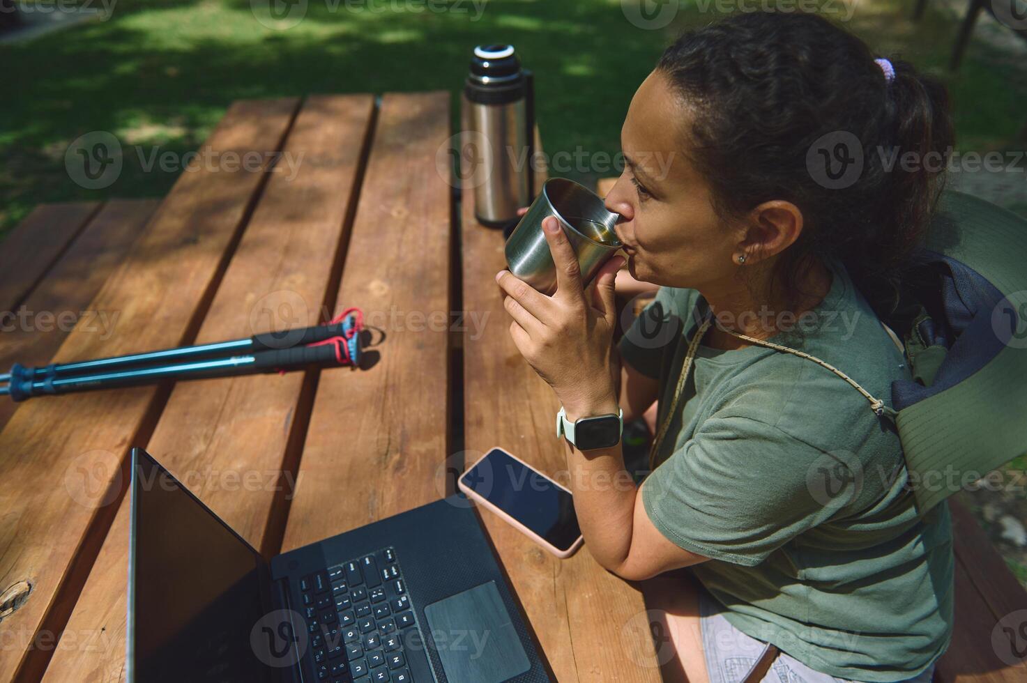 Digital Nomad Working Outdoors in a Mountain Setting with Laptop and Beverage photo