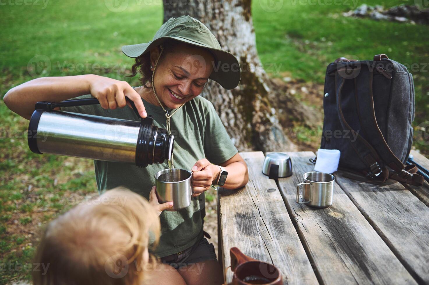 Woman Enjoying Outdoor Picnic With Child and Pouring Drinks photo