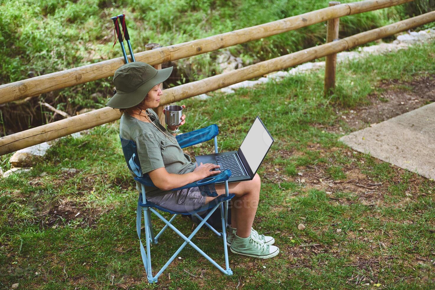 Woman Working Remotely Outdoors With Laptop in a Nature Setting photo