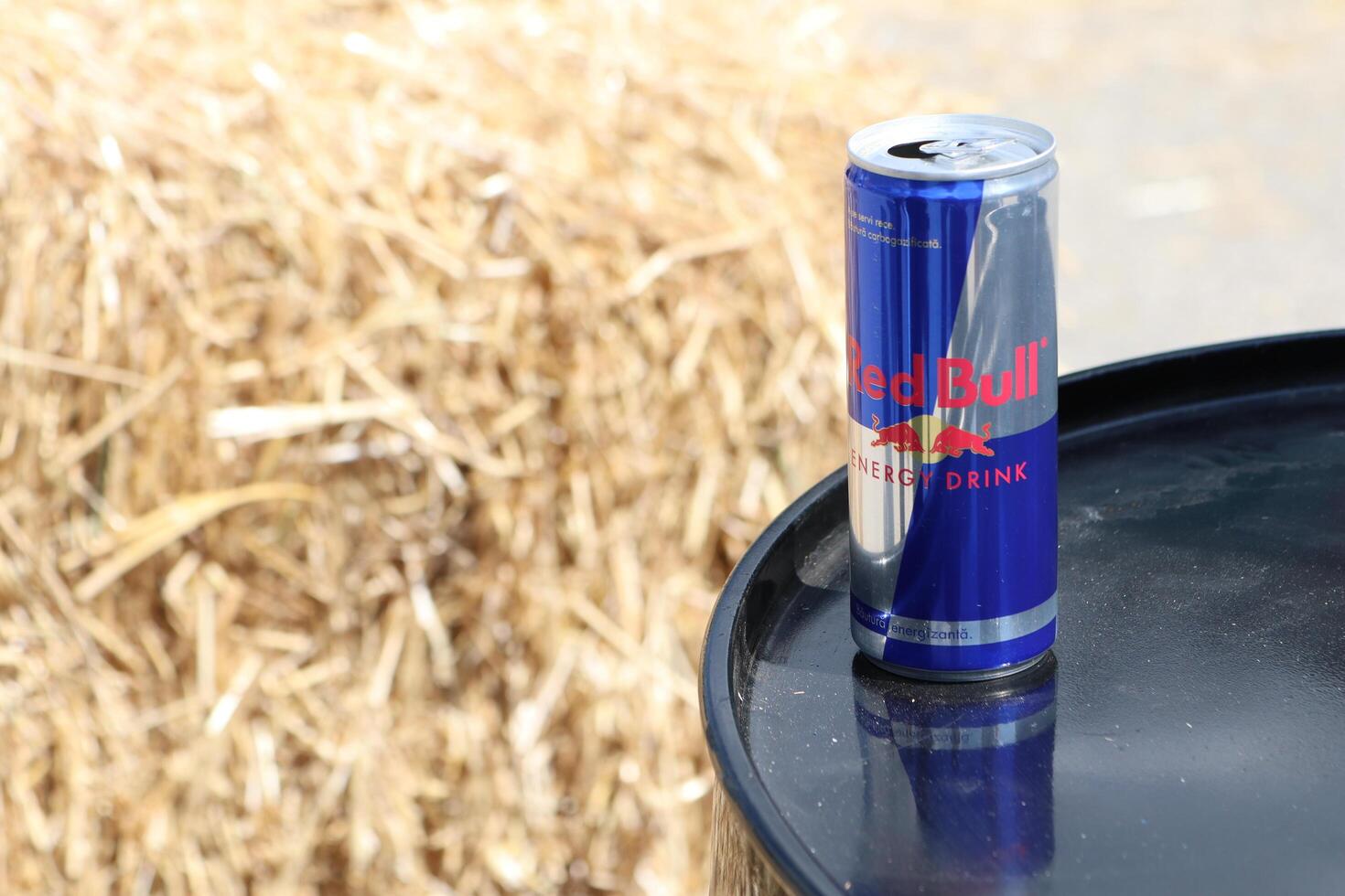 09.3.2025 Moldova An Energy Drink Can rests atop a Rustic Barrel surrounded by fresh, golden Hay in nature photo