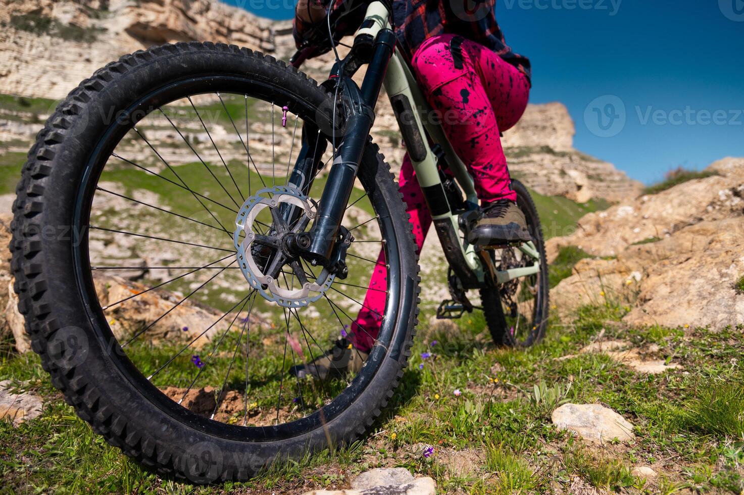 Close up of extreme mountain biking, cyclist riding off-piste in green field with mountains in background, outdoor fun and enjoying riding photo