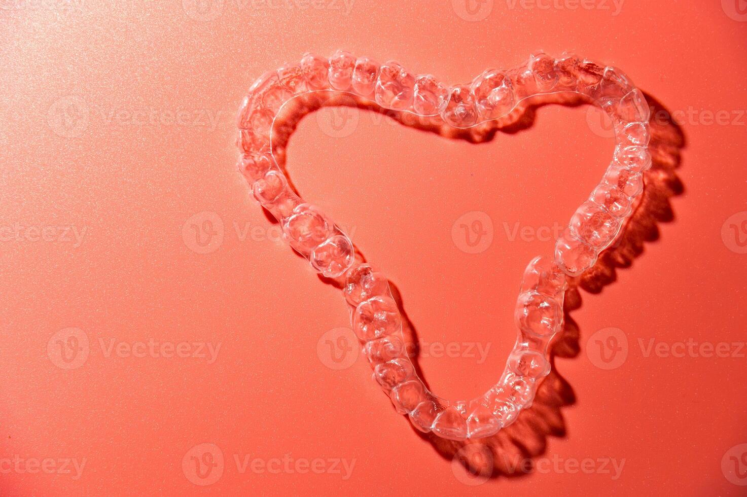 Close up of invisible aligners on pink background with copy space. Plastic braces dental retainers for teeth straightening photo