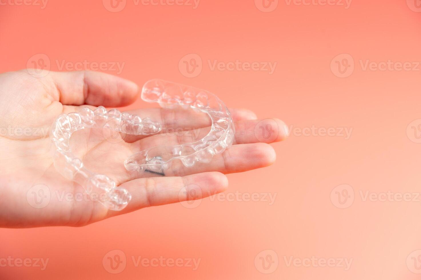 female patient holds two transparent dental aligners in her palms. concept of equal healthy teeth photo
