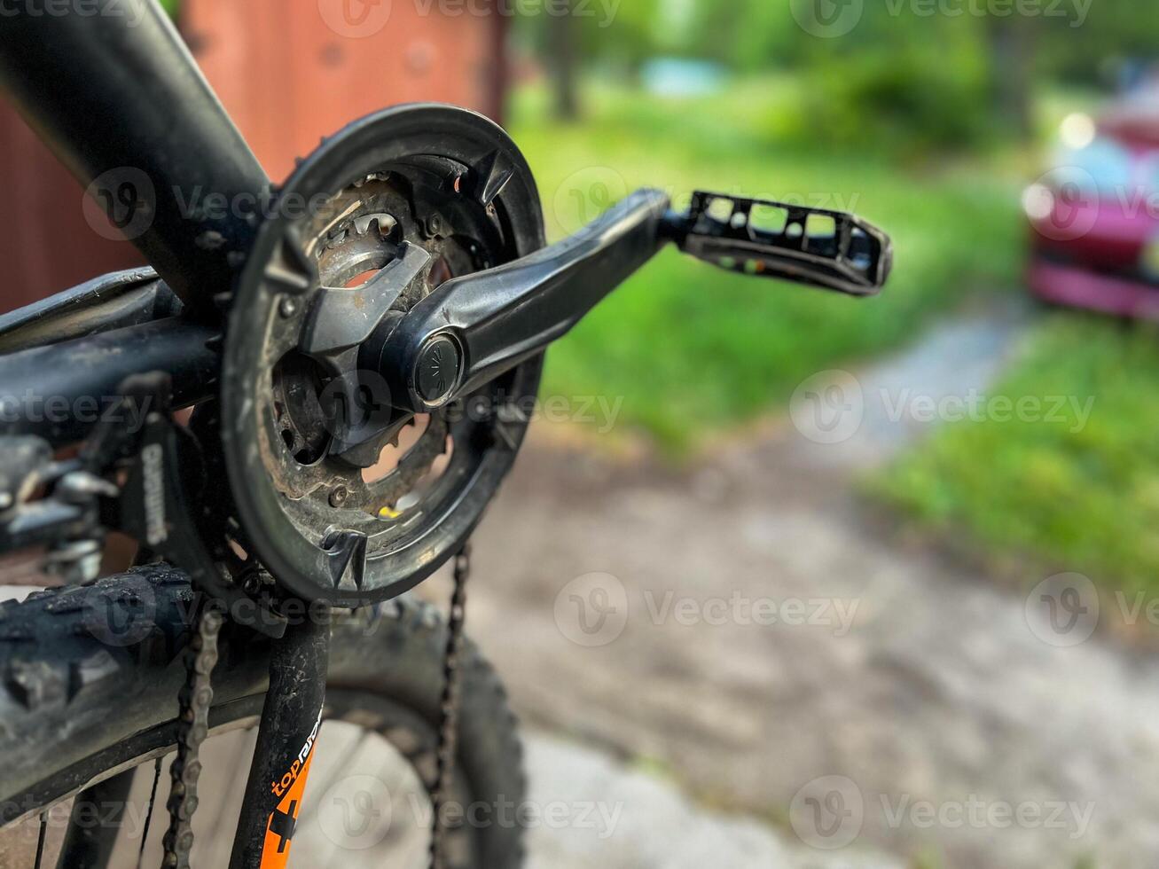 Close-up of dirty bicycle crankset and pedal with blurred background photo