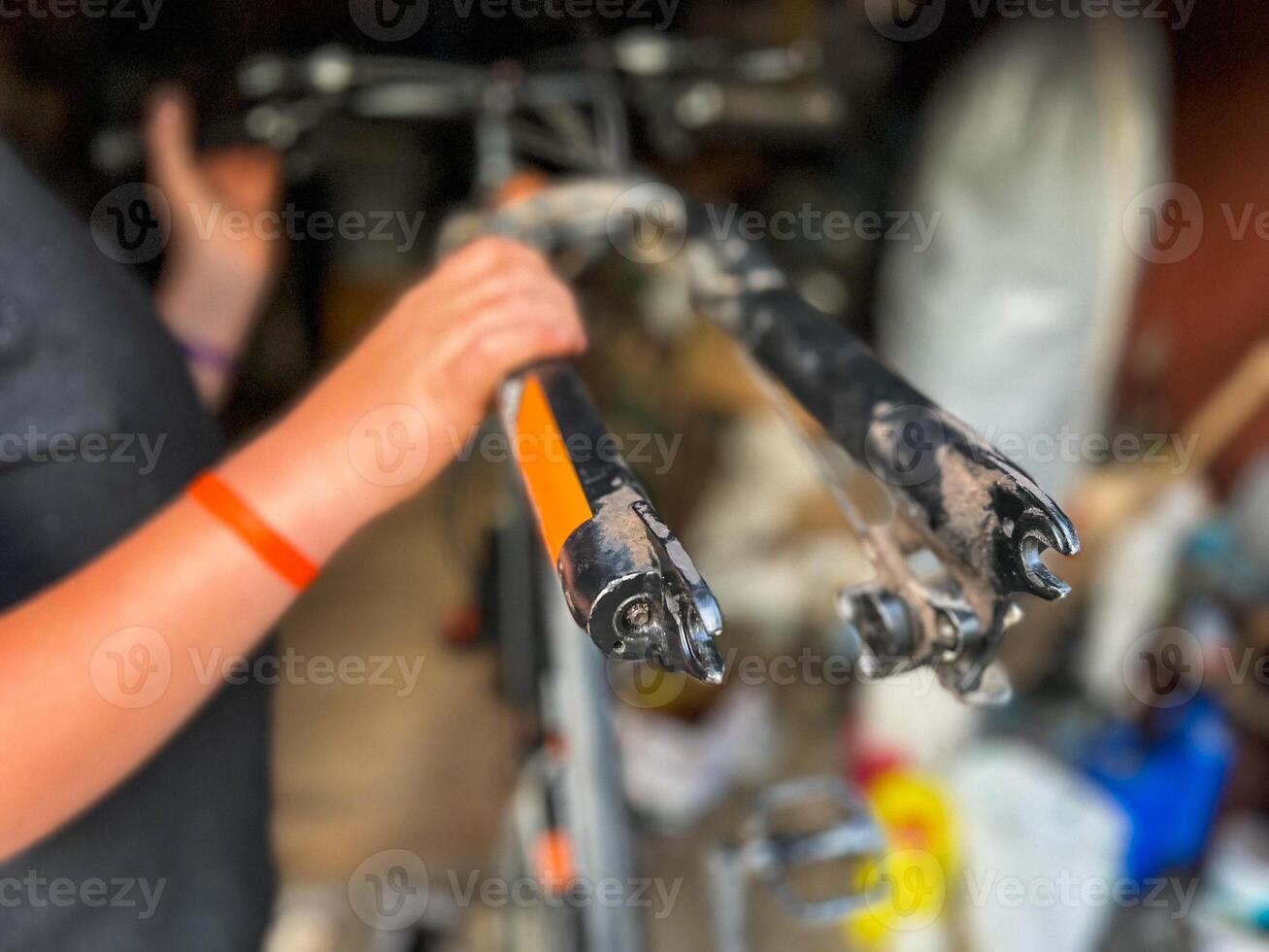 Mechanic holding and inspecting damaged bicycle fork in workshop photo