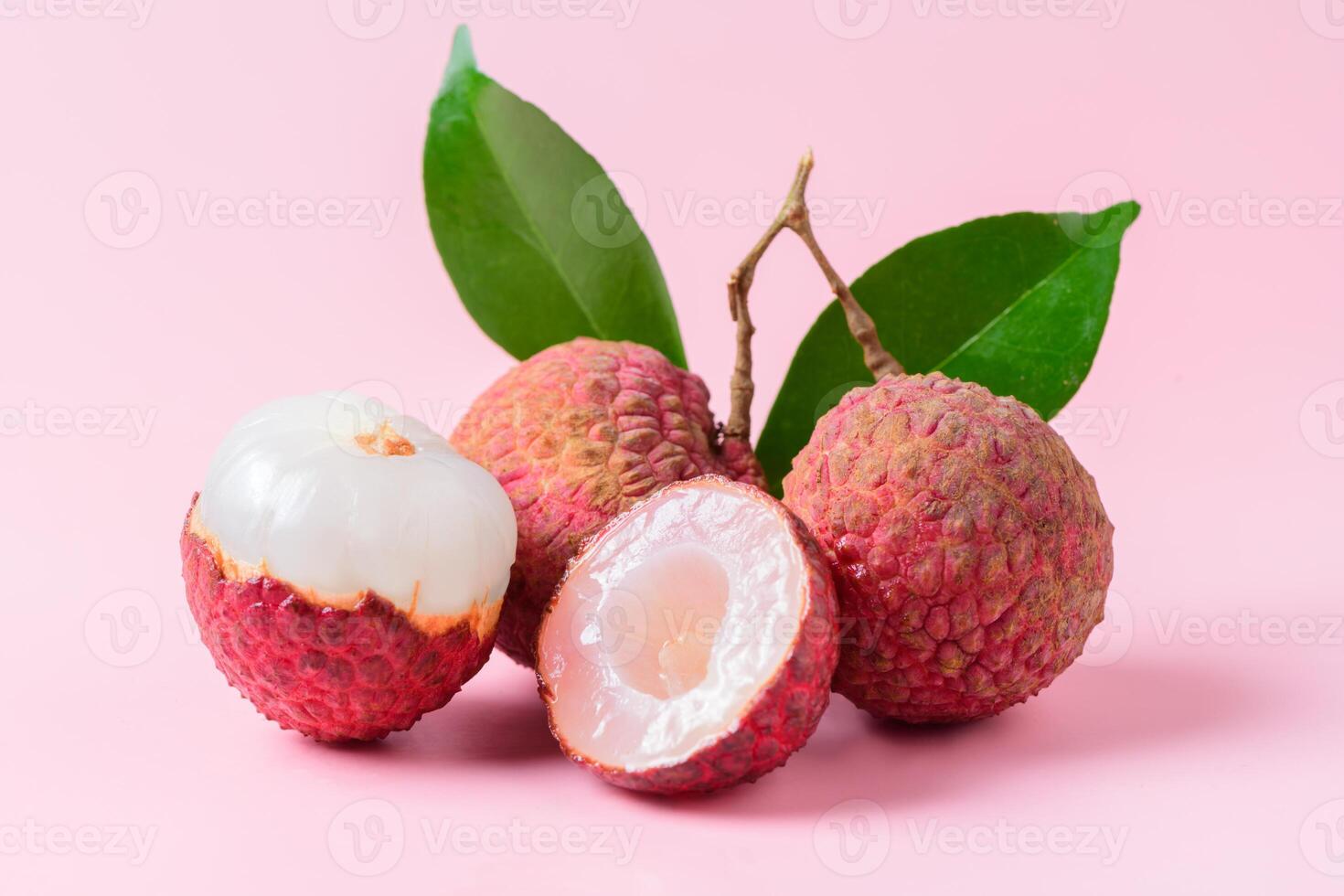 Juicy Lychee with cut in half and leaves isolated on pink background.. photo