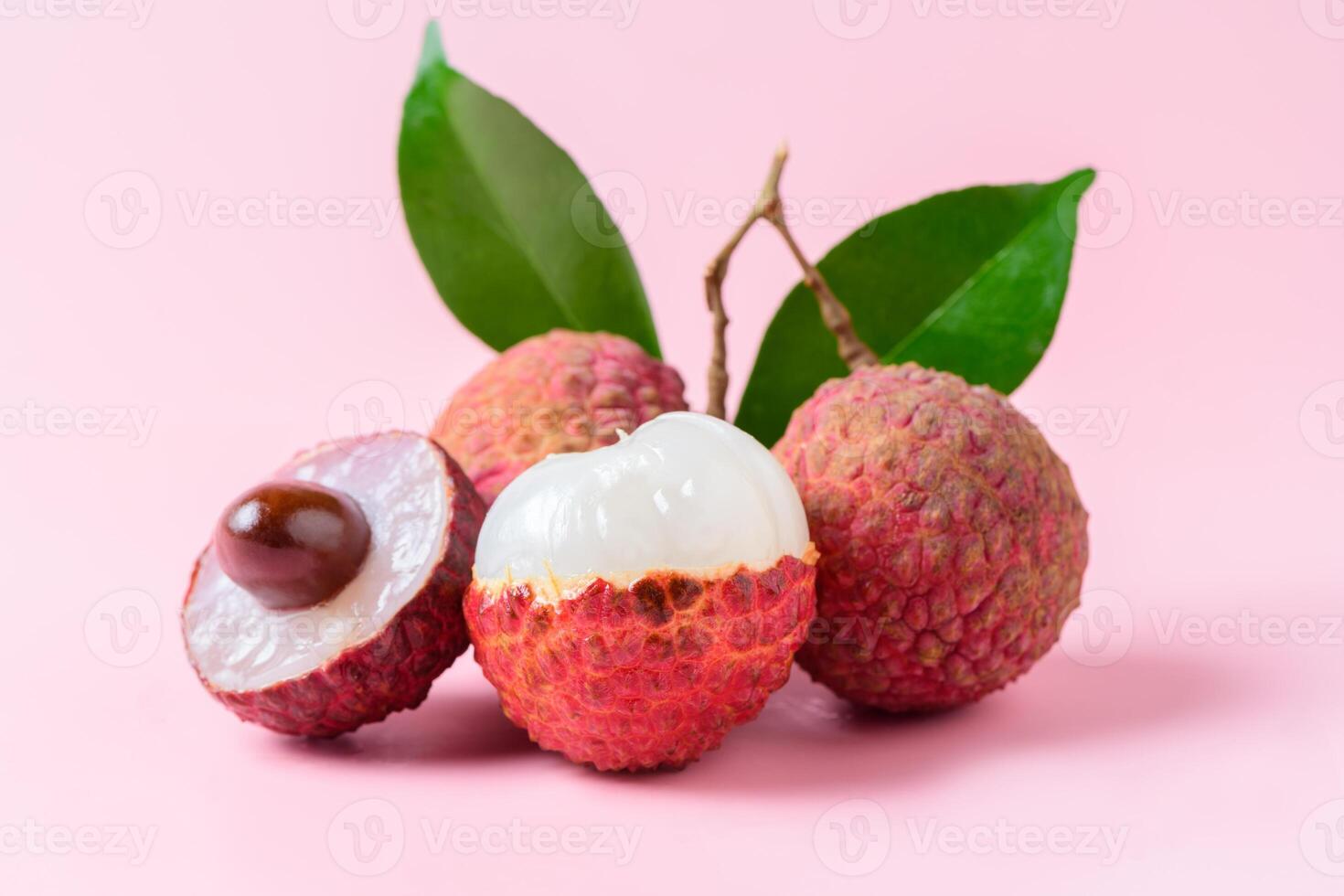 Juicy Lychee with cut in half and leaves isolated on pink background. photo
